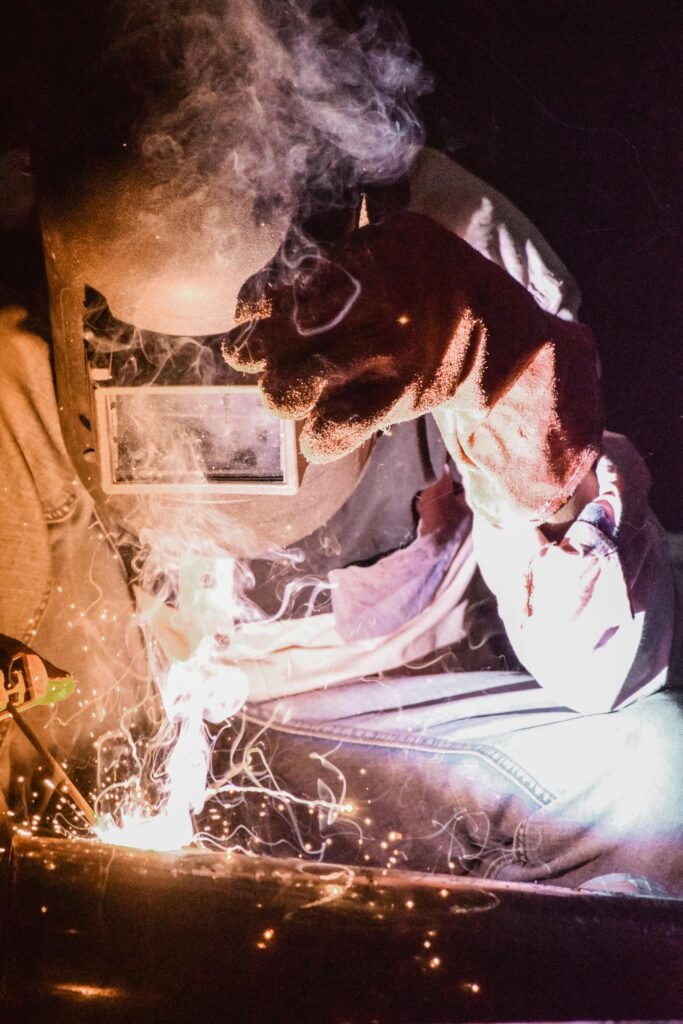 A welder in protective gear works with intense sparks during welding, showcasing skill and precision.